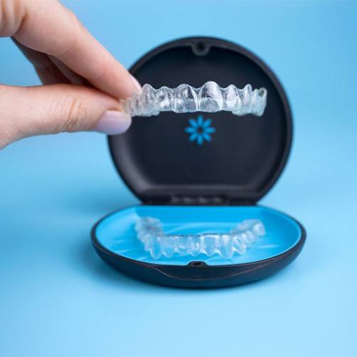 Close up of patient lifting an Invisalign tray from its case