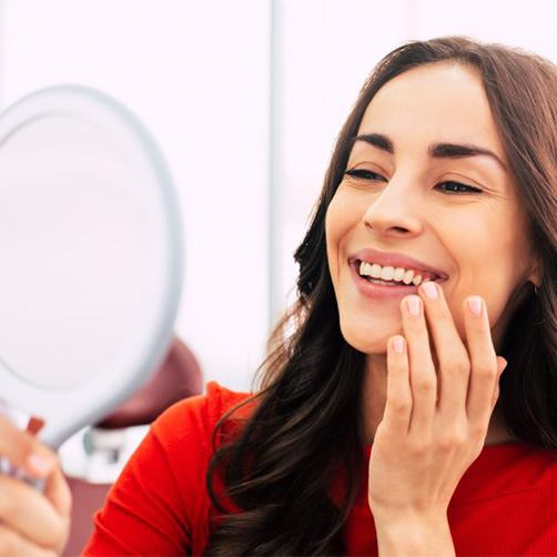 Woman admiring her straight teeth in a small mirror