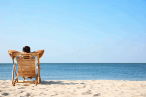 Man in beach chair relaxing as he faces the beach